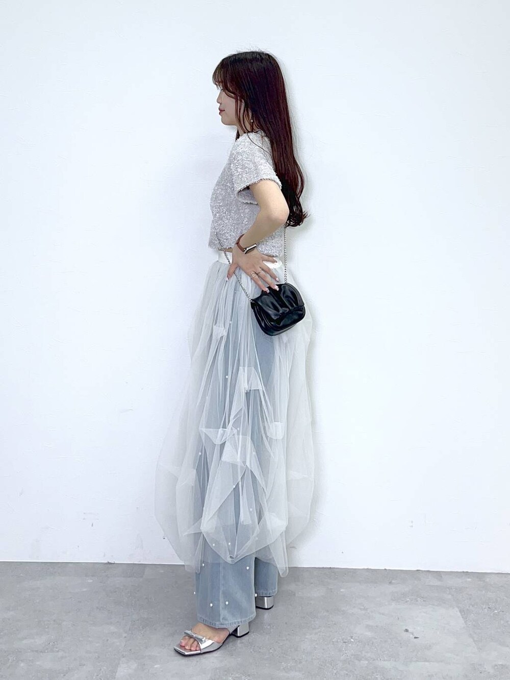 ブラック系のショルダーバッグ、ブルー系のデニムパンツ、ホワイト系のキャミソールを着用したレディースの春コーディネートの3枚目の写真