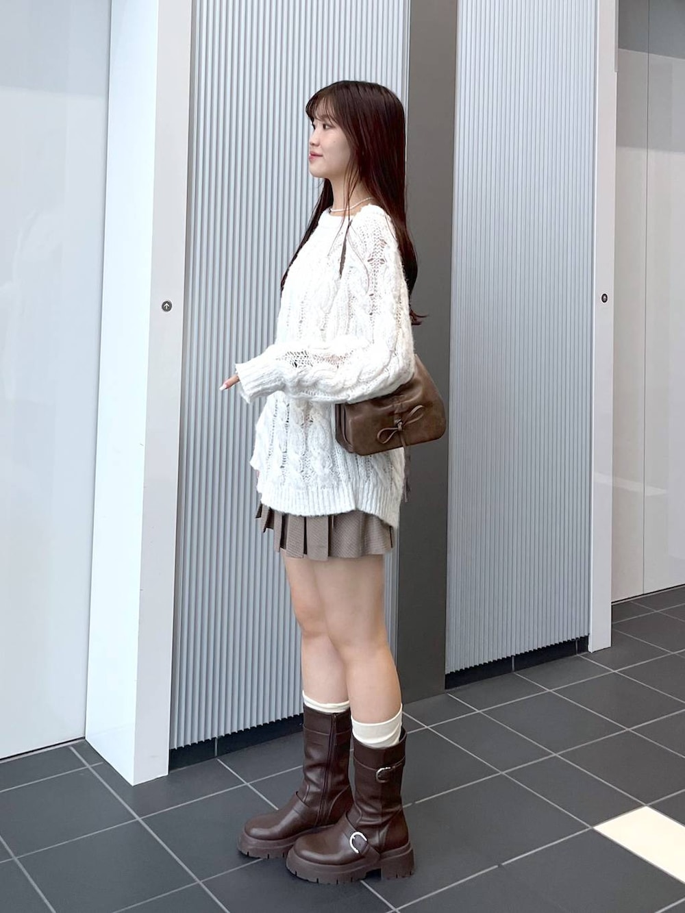 ブラウン系のショルダーバッグ、ブラウン系のブーツ、ホワイト系のキャミソールを着用したレディースの秋コーディネートの6枚目の写真