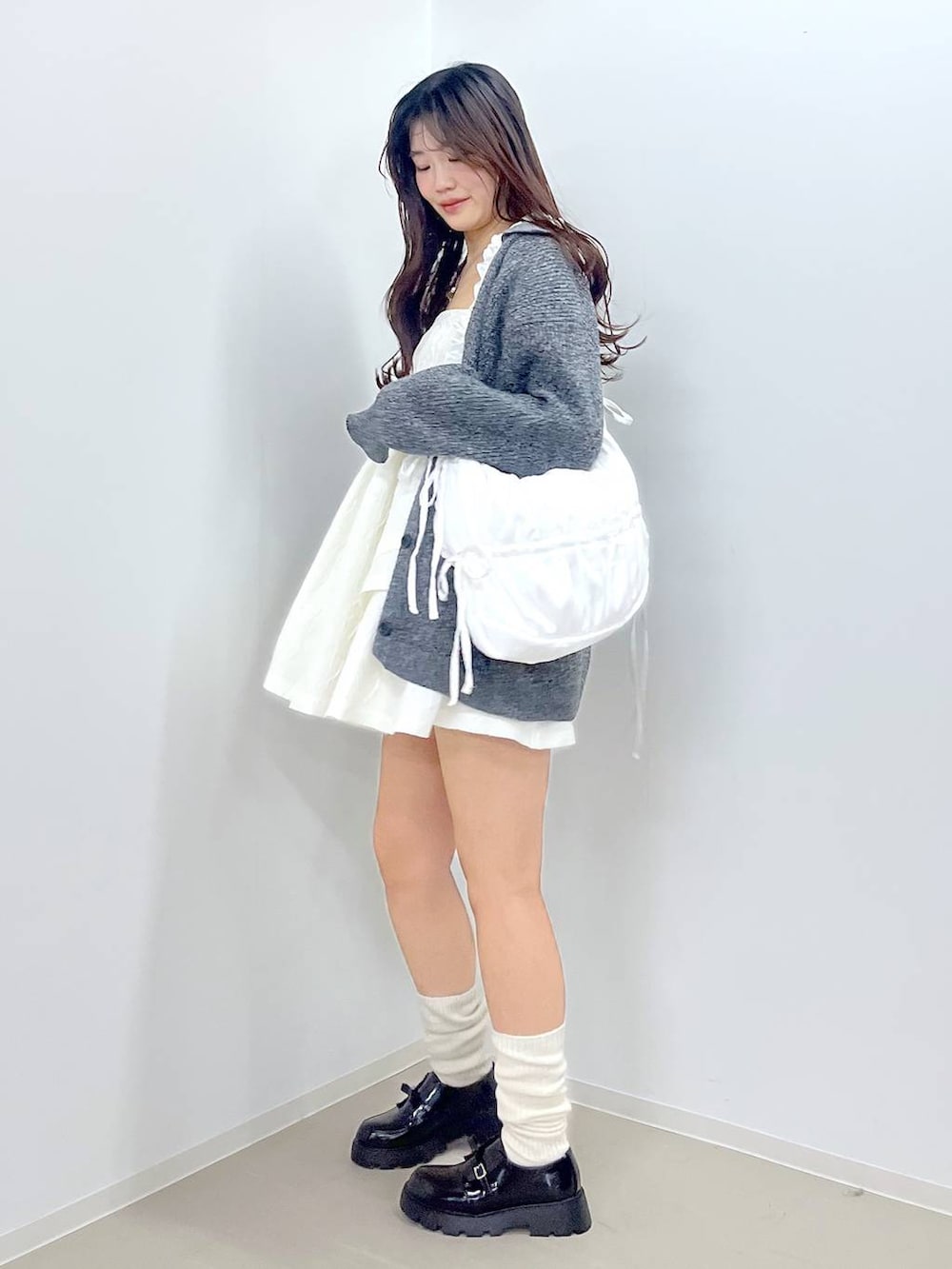 ブラック系のドレスシューズ、ホワイト系のワンピース、ホワイト系のショルダーバッグを着用したレディースの春コーディネートの3枚目の写真