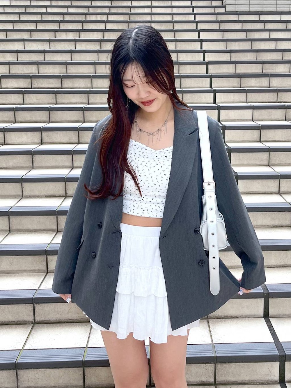 ホワイト系のキャミソール、ホワイト系のスカート、ブラック系のブーツを着用したレディースの春コーディネートの6枚目の写真