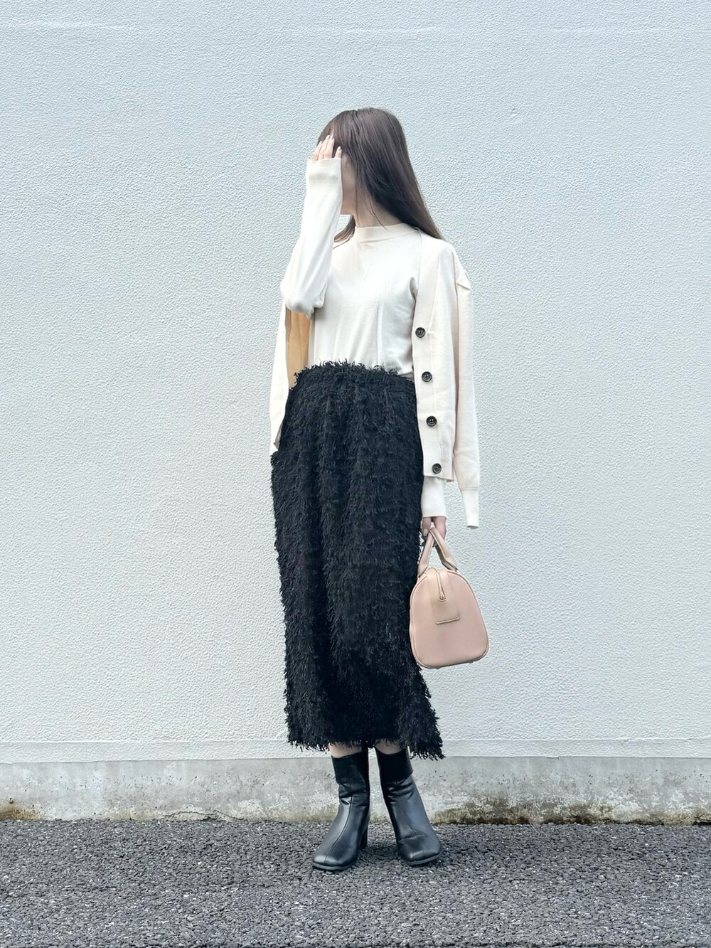 ブラック系のスカート、ブラック系のブーツ、グレー系のスマホグッズを着用したレディースの秋コーディネートの5枚目の写真