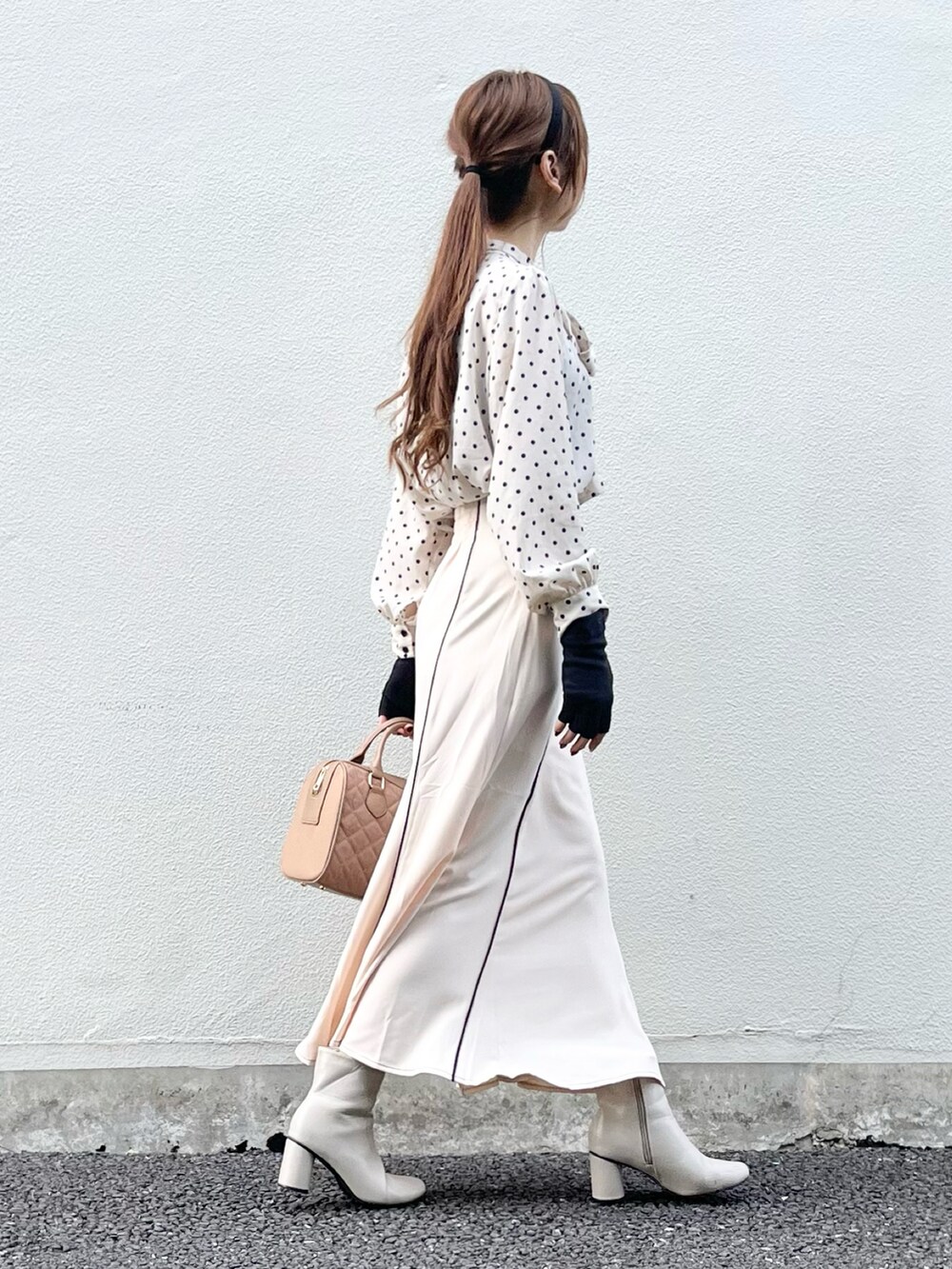 ベージュ系のスカート、ベージュ系のハンドバッグ、ホワイト系のブーツを着用したレディースの秋コーディネートの5枚目の写真