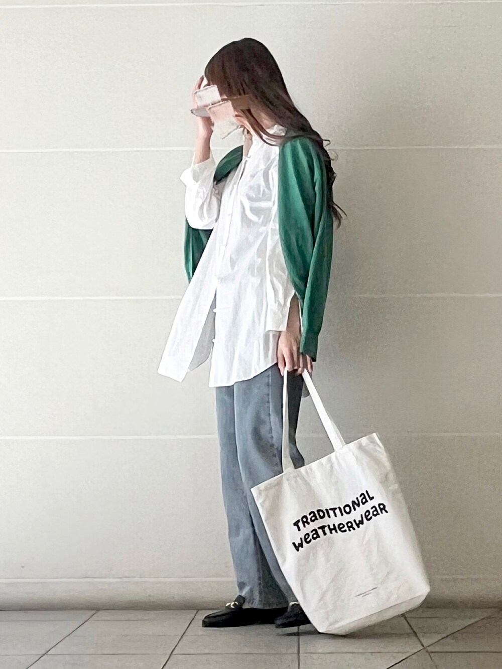 ブラック系のローファー、ホワイト系のトートバッグ、グリーン系のカーディガン/ボレロを着用したレディースの春コーディネートの2枚目の写真