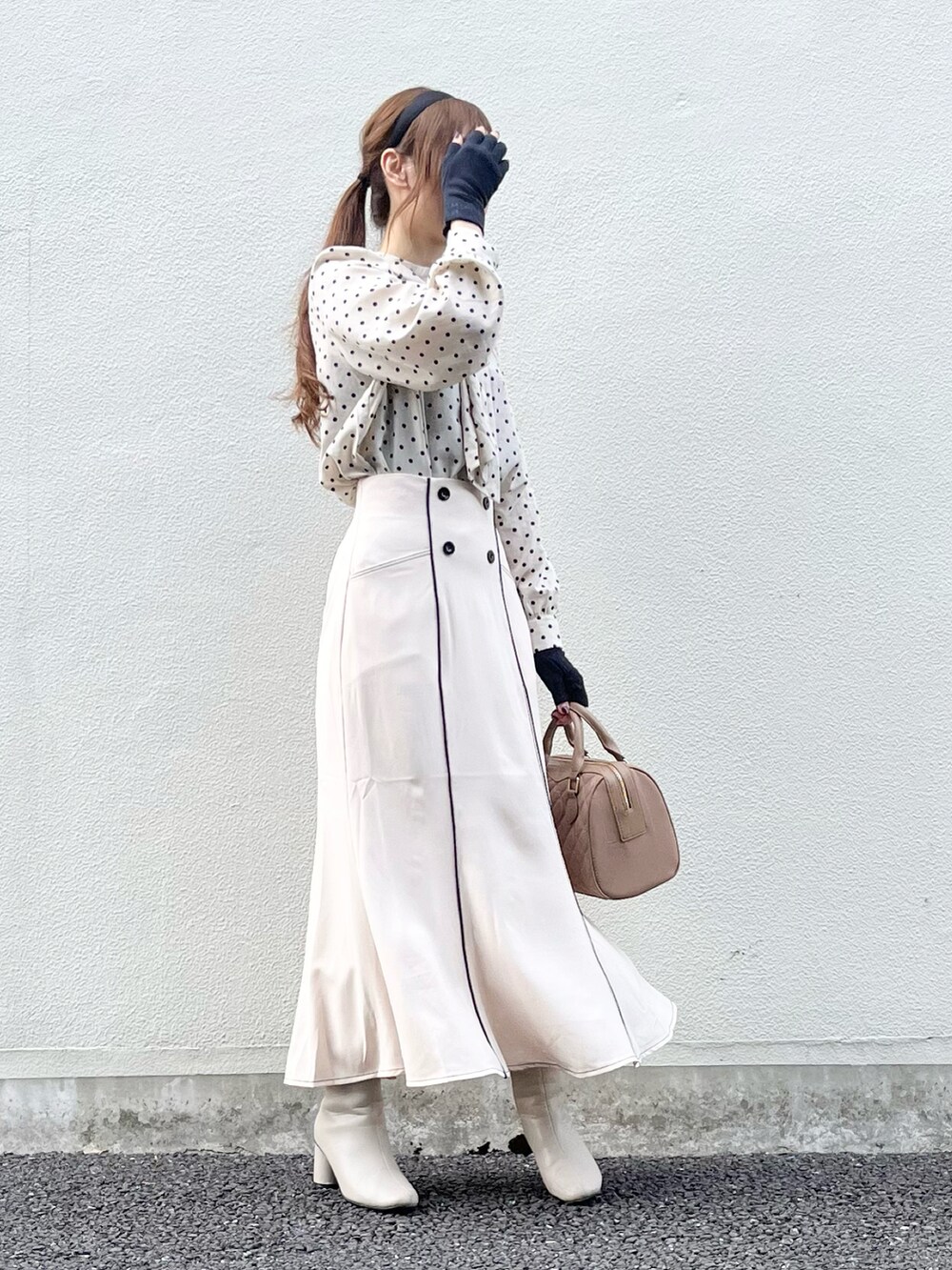 ベージュ系のスカート、ベージュ系のハンドバッグ、ホワイト系のブーツを着用したレディースの秋コーディネートの4枚目の写真