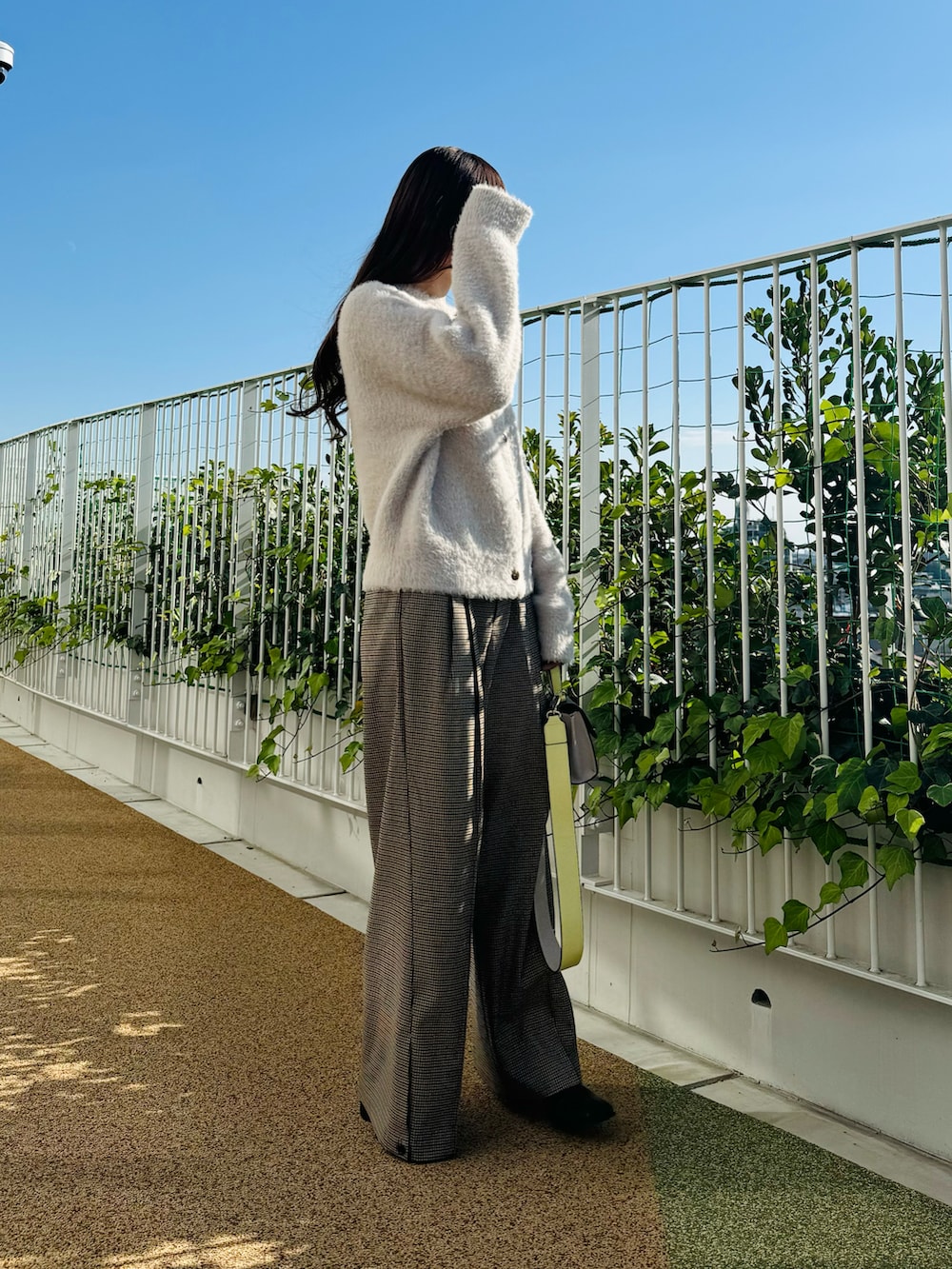 ピンク系のハンドバッグ、ブラック系のブーツ、ベージュ系のカーディガン/ボレロを着用したレディースの秋コーディネートの4枚目の写真