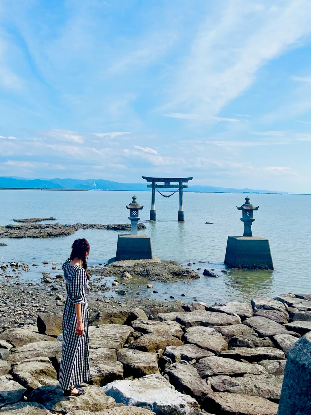 ブラック系のワンピース、ブラック系のサンダル、グレー系のスマホグッズを着用したレディースの夏コーディネートの2枚目の写真