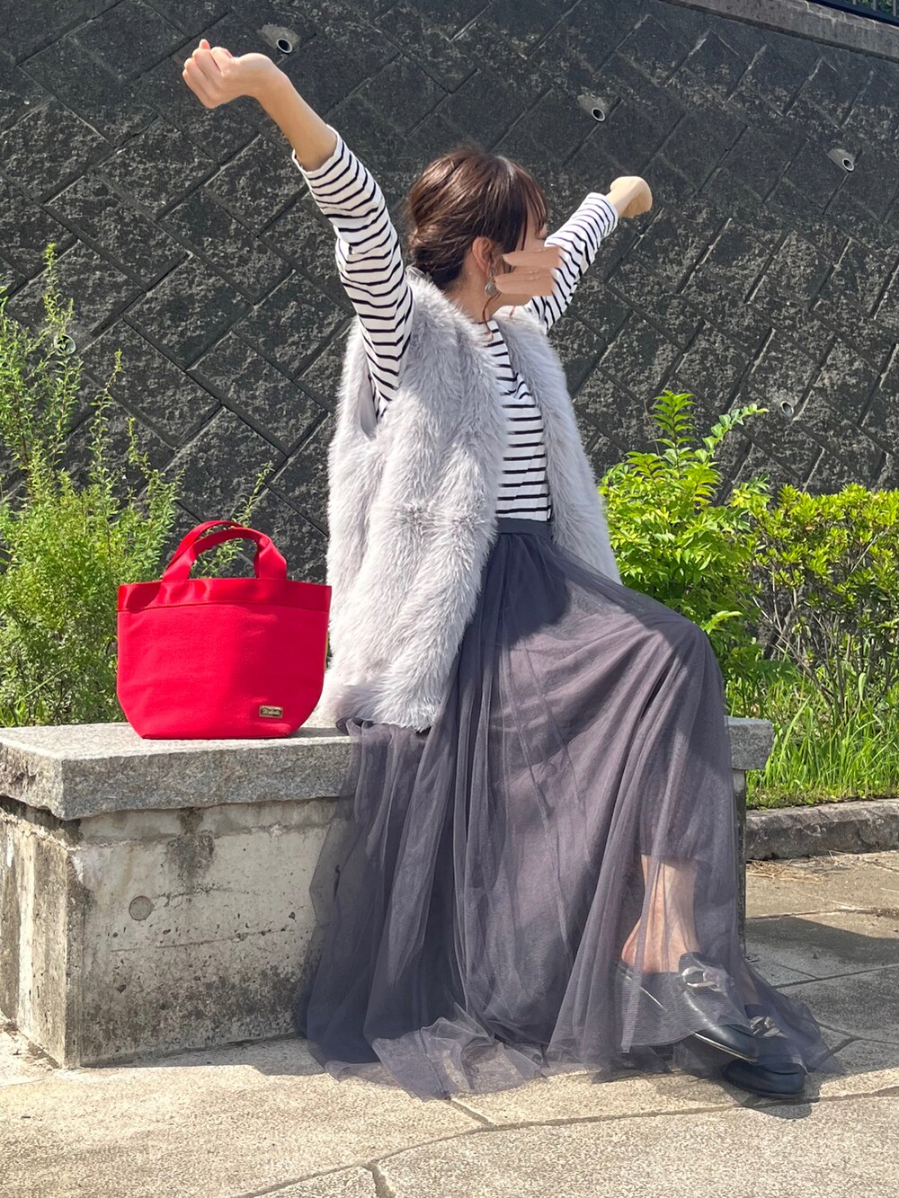 グレー系のベスト、ブラック系のスリッポン、グレー系のスカートを着用したレディースの秋コーディネートの4枚目の写真