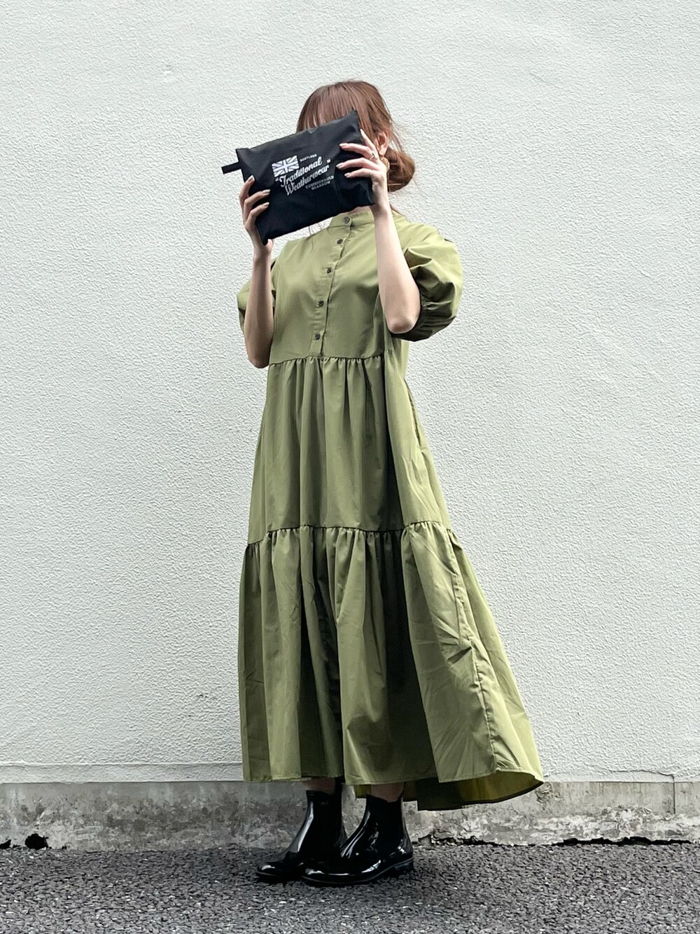 ブラック系のレインシューズ、グリーン系のワンピース、ブラック系のレインコート/ポンチョを着用したレディースの春コーディネートの2枚目の写真