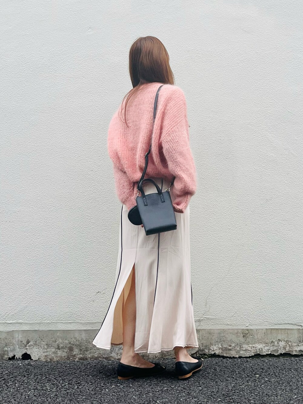 ピンク系のニット/セーター、ベージュ系のスカート、ブラック系のバレエシューズを着用したレディースの春コーディネートの2枚目の写真