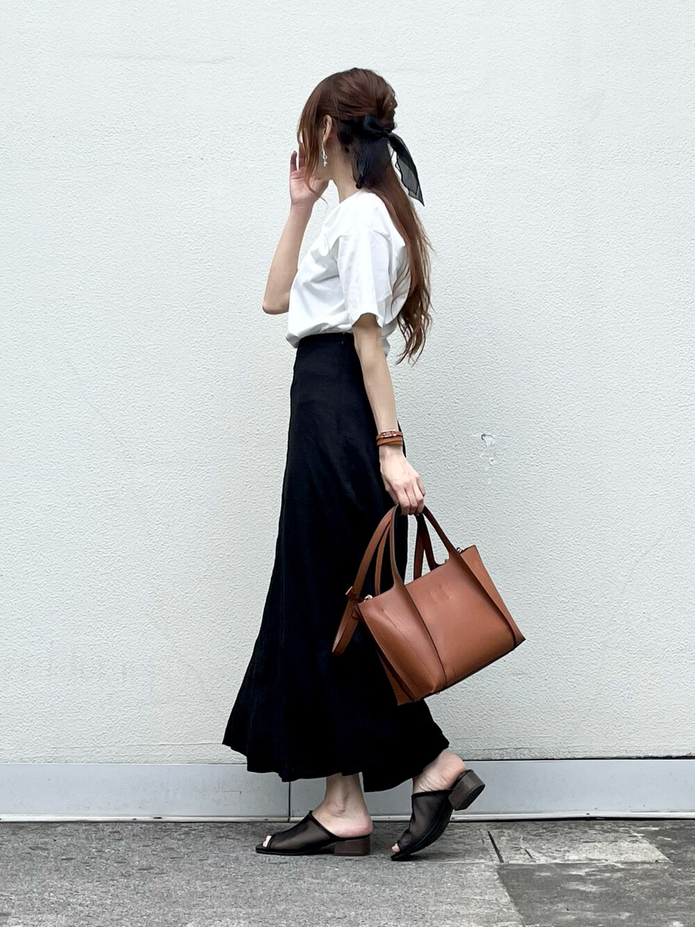 ブラウン系のバッグ、ブラック系のスカート、ブラック系のその他シューズを着用したレディースの夏コーディネートの2枚目の写真
