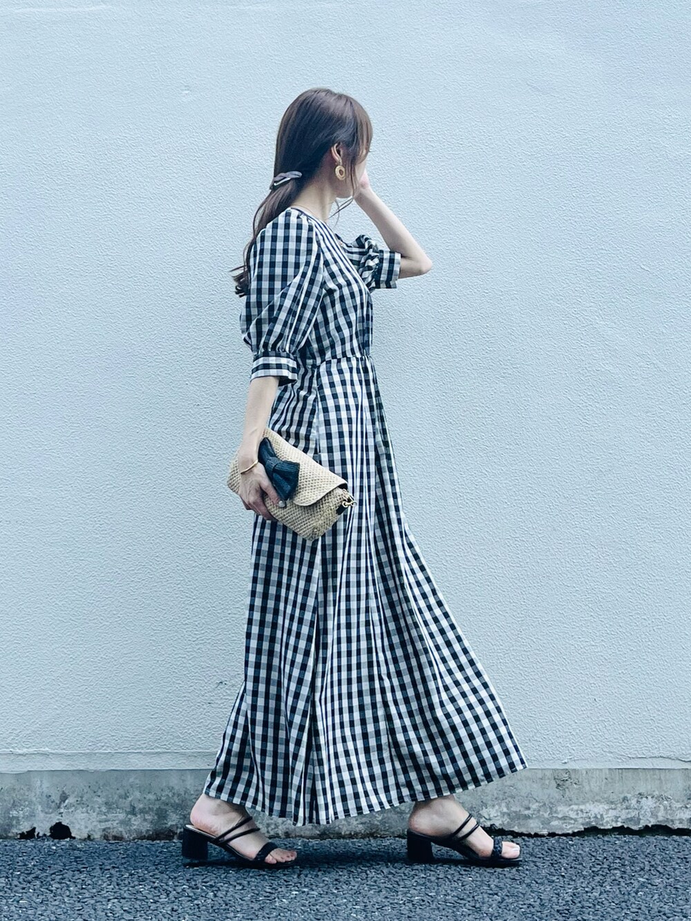 ブラック系のワンピース/ドレス、ベージュ系のバッグ、ブラック系のサンダルを着用したレディースの春コーディネートの2枚目の写真