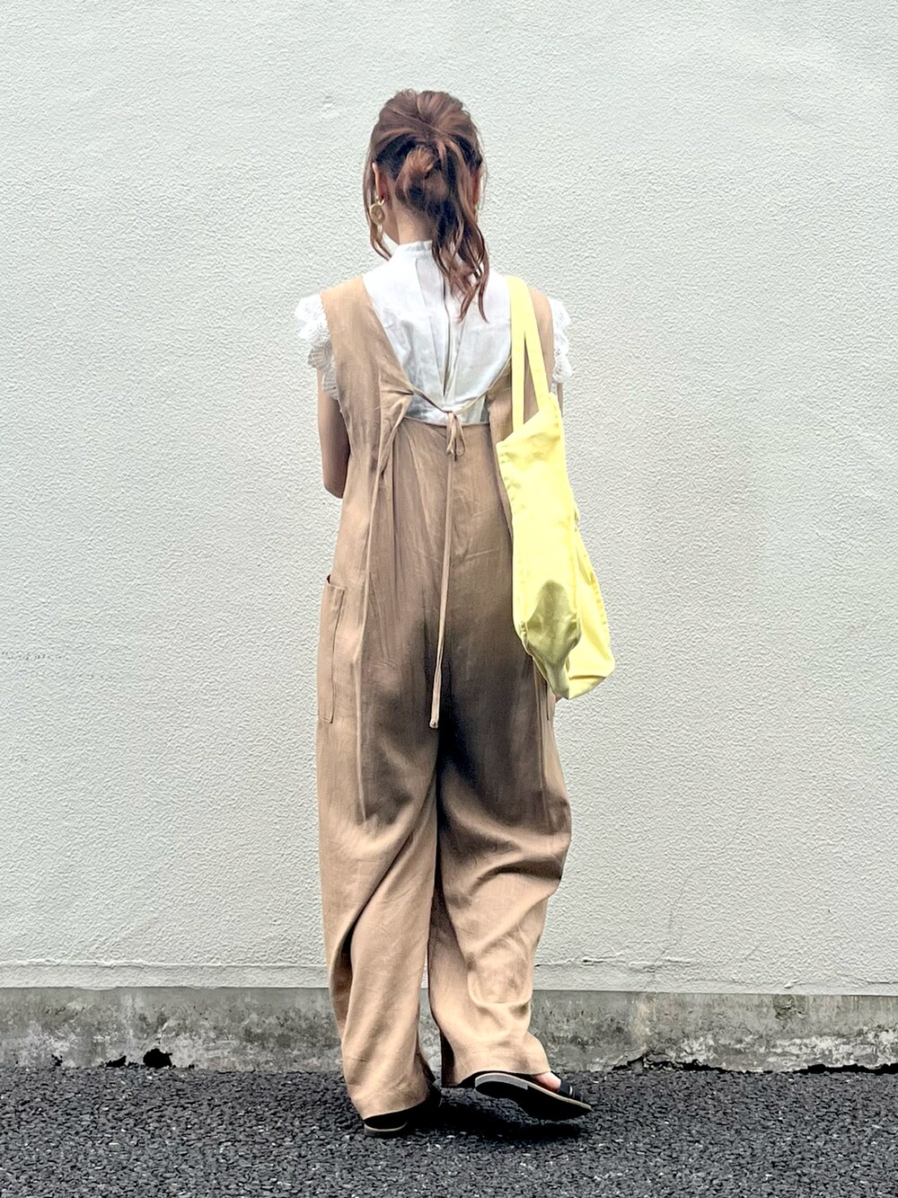 イエロー系のトートバッグ、ベージュ系のサロペット/オーバーオール、ホワイト系のシャツ/ブラウスを着用したレディースの夏コーディネートの2枚目の写真