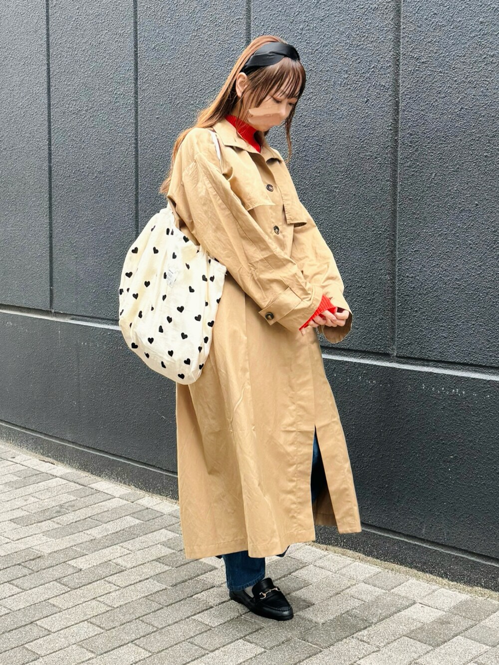 ベージュ系のステンカラーコート、レッド系のニット/セーター、ブラック系のローファーを着用したレディースの春コーディネートの3枚目の写真