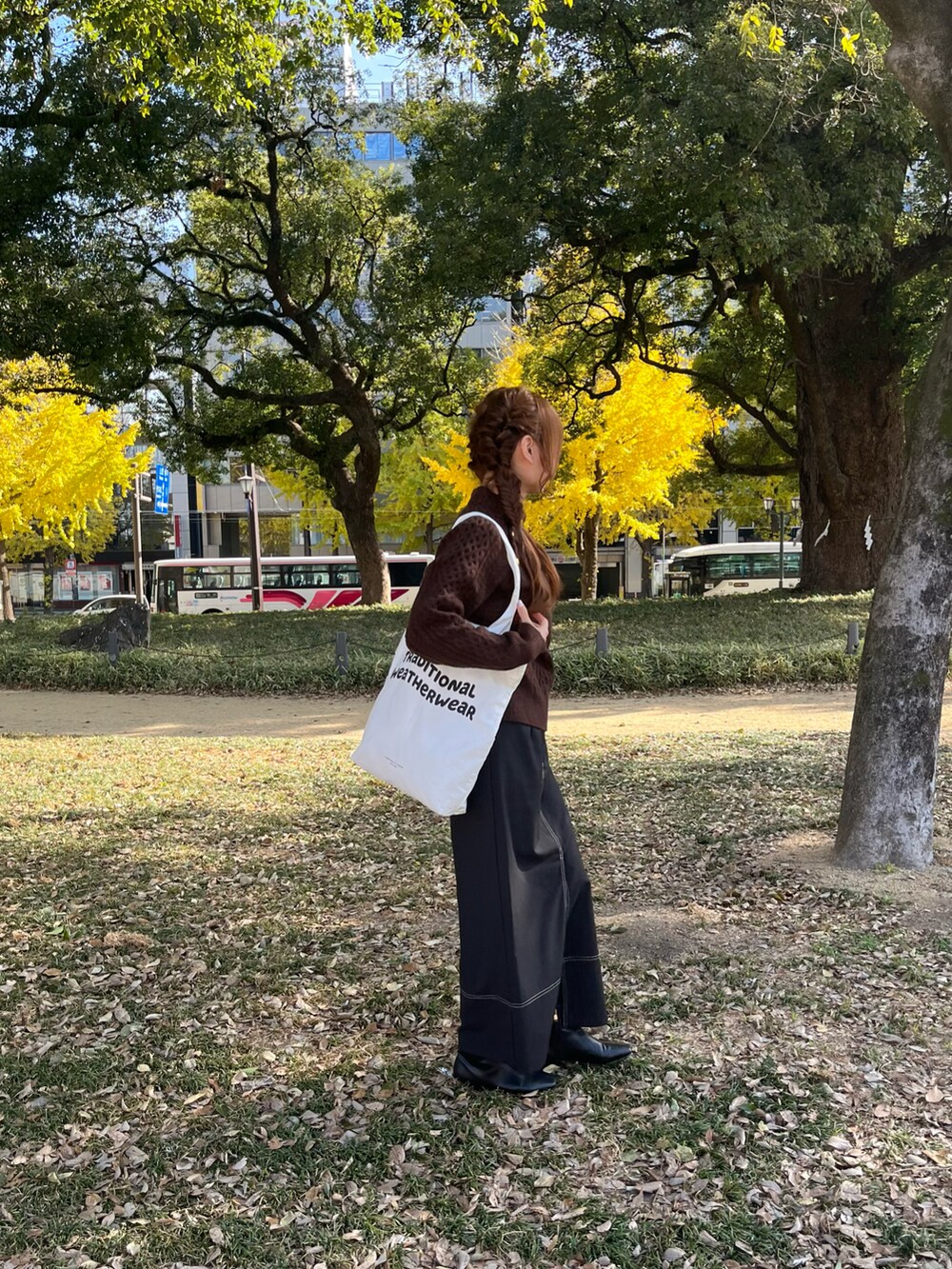 ホワイト系のトートバッグ、ブラック系のスカート、ブラック系のブーツを着用したレディースの冬コーディネートの4枚目の写真