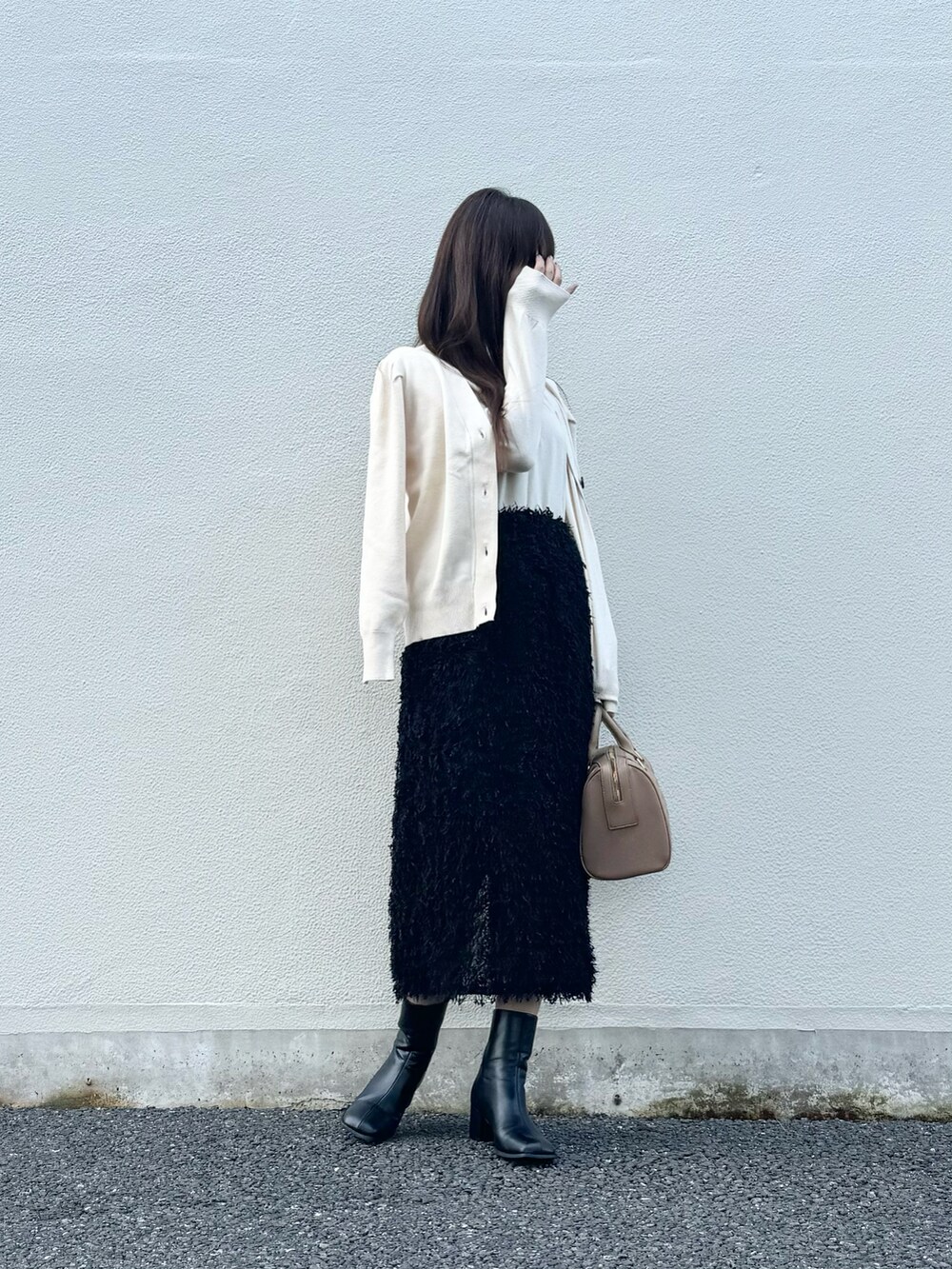 ブラック系のスカート、ブラック系のブーツ、グレー系のスマホグッズを着用したレディースの秋コーディネートの4枚目の写真