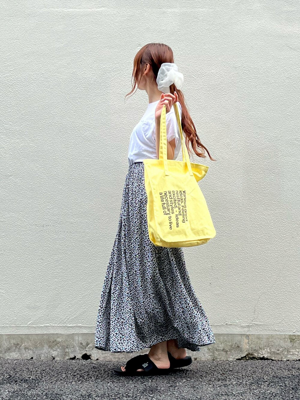 イエロー系のトートバッグ、ホワイト系のTシャツ/カットソー、ブラック系のスカートを着用したレディースの夏コーディネートの3枚目の写真