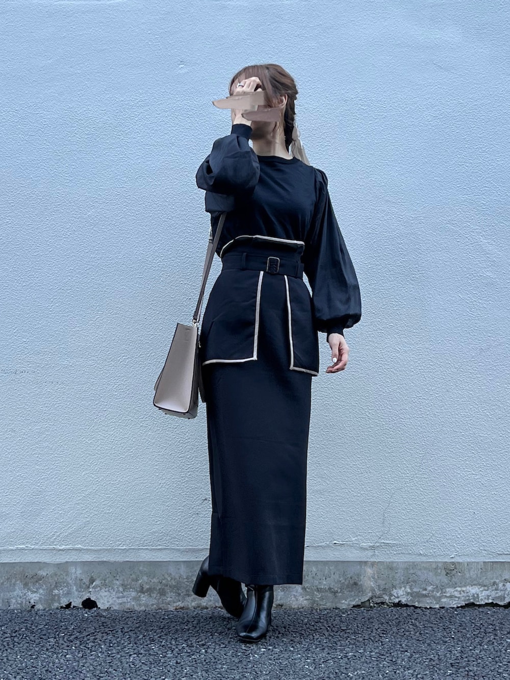 ブラック系のスカート、ベージュ系のバッグ、ブラック系のニット/セーターを着用したレディースの秋コーディネートの5枚目の写真