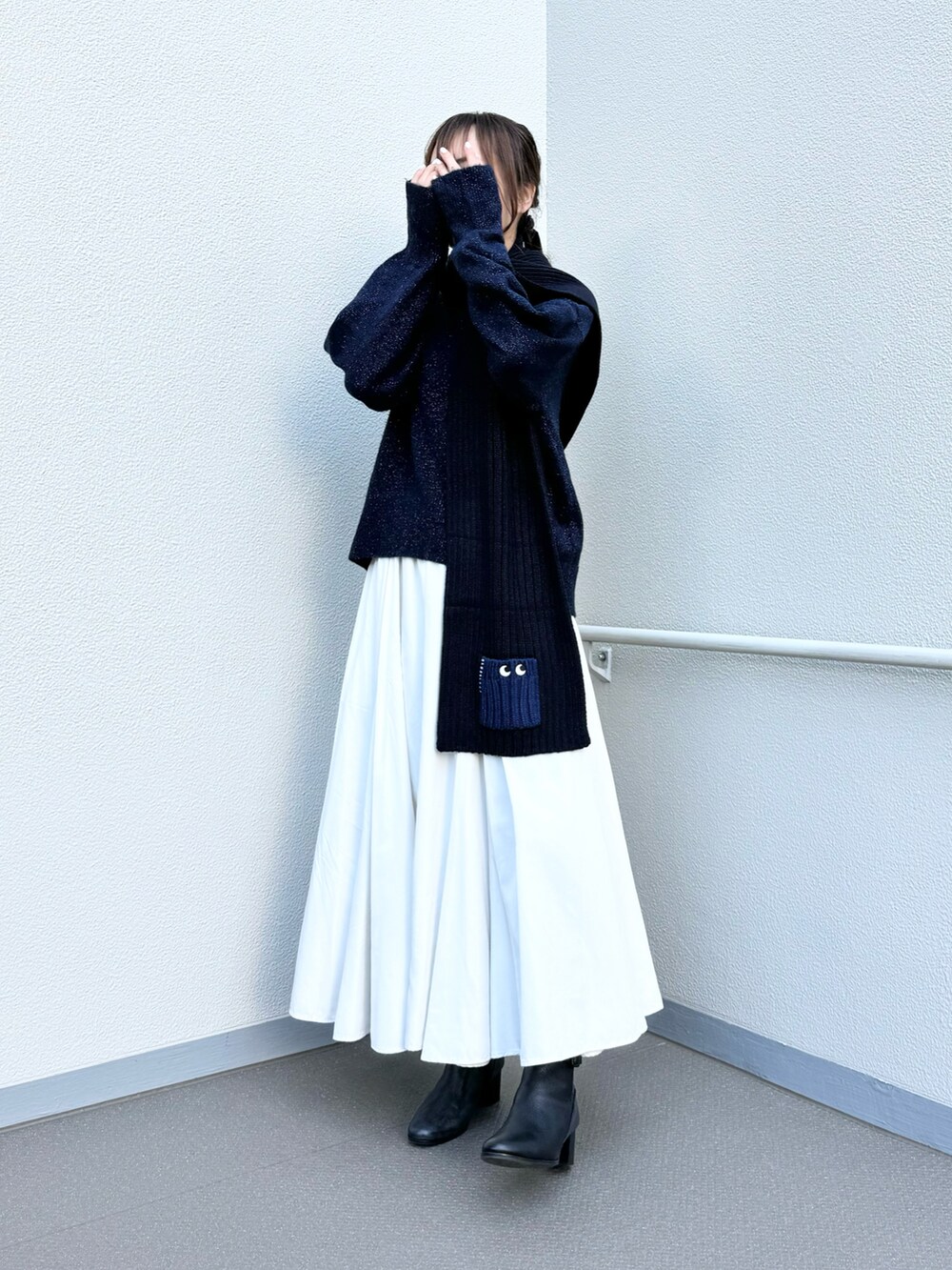 ブラック系のブーツ、ブルー系のニット/セーター、ホワイト系のスカートを着用したレディースの冬コーディネートの2枚目の写真