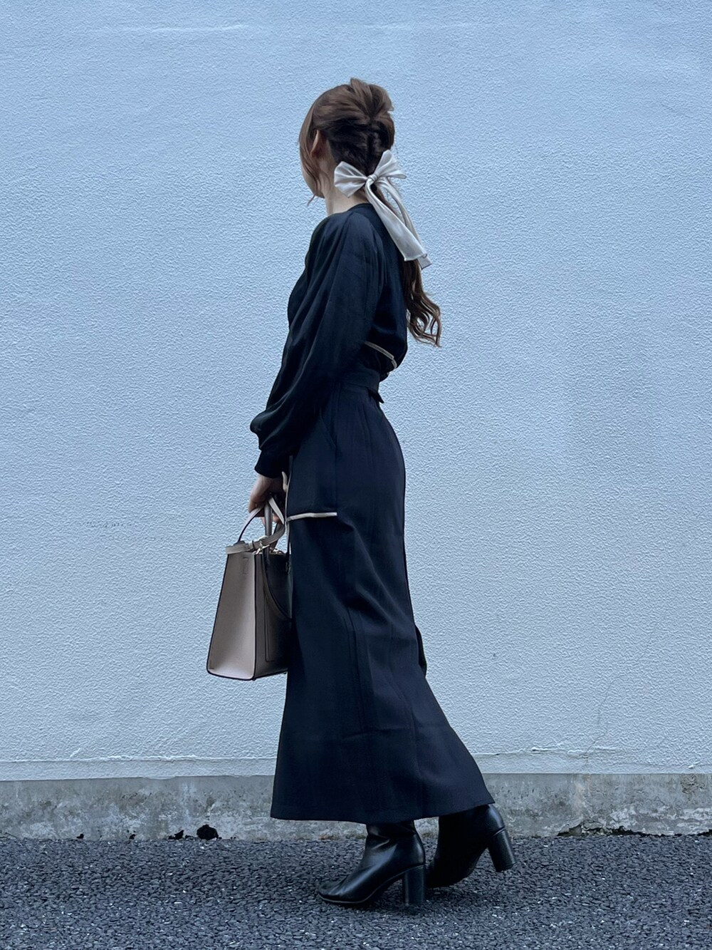 ブラック系のスカート、ベージュ系のバッグ、ブラック系のニット/セーターを着用したレディースの秋コーディネートの3枚目の写真