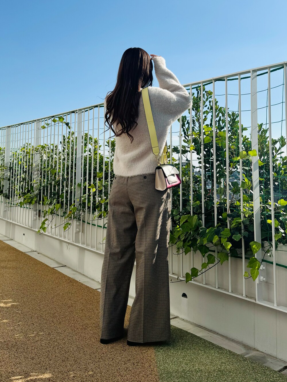 ピンク系のハンドバッグ、ブラック系のブーツ、ベージュ系のカーディガン/ボレロを着用したレディースの秋コーディネートの2枚目の写真