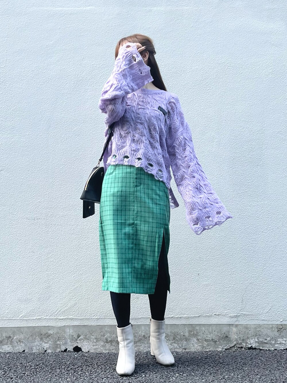 パープル系のニット/セーター、グリーン系のスカート、ブラック系のハンドバッグを着用したレディースの秋コーディネートの2枚目の写真