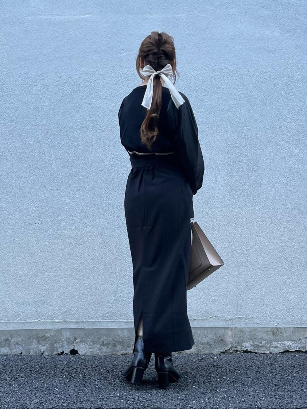 ブラック系のスカート、ベージュ系のバッグ、ブラック系のニット/セーターを着用したレディースの秋コーディネートの2枚目の写真