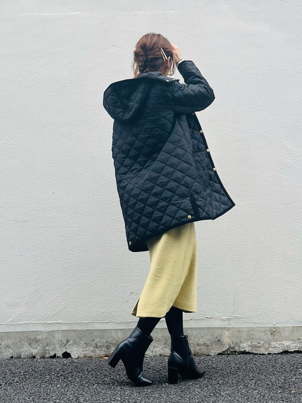 ブラック系のノーカラーコート、ホワイト系のTシャツ/カットソー、イエロー系のスカートを着用したレディースの秋コーディネートの2枚目の写真