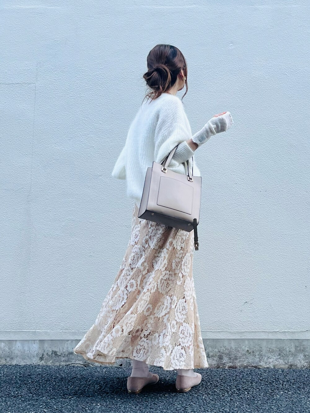 ベージュ系のスカート、ホワイト系のニット/セーター、ベージュ系のバッグを着用したレディースの春コーディネートの2枚目の写真
