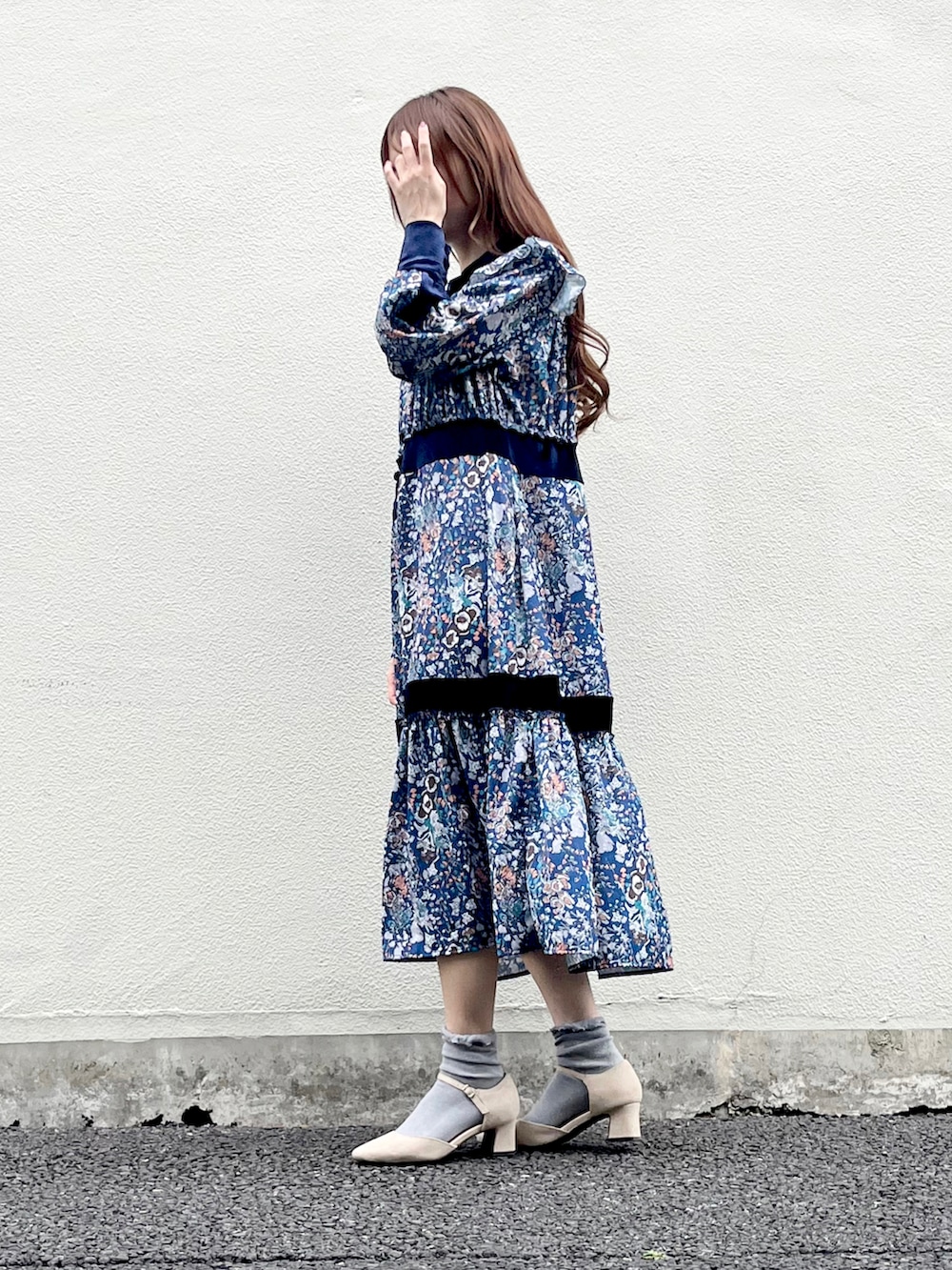 ベージュ系のパンプス、ブルー系のワンピース、ベージュ系のレインコート/ポンチョを着用したレディースの春コーディネートの2枚目の写真