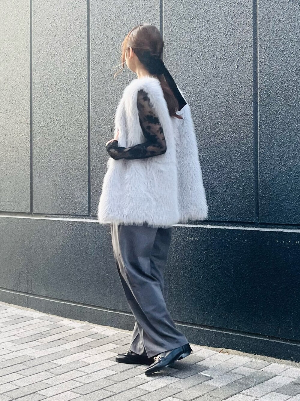 グレー系のベスト、ブラック系のショルダーバッグ、ブラック系のローファーを着用したレディースの冬コーディネートの3枚目の写真