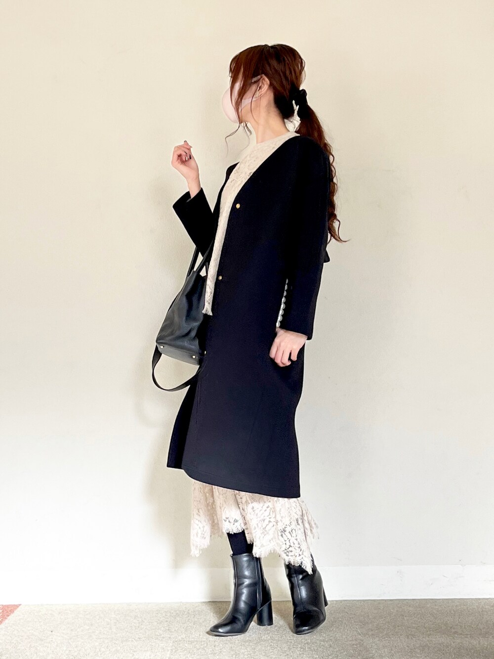 ブラック系のノーカラーコート、ブラック系のトートバッグ、グレー系のシャツ/ブラウスを着用したレディースの冬コーディネートの2枚目の写真