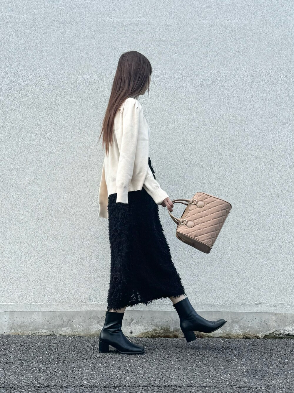 ブラック系のスカート、ブラック系のブーツ、グレー系のスマホグッズを着用したレディースの秋コーディネートの2枚目の写真