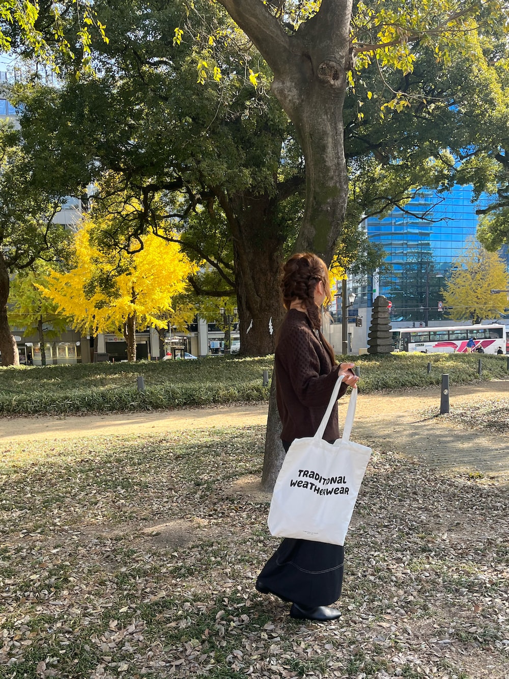 ホワイト系のトートバッグ、ブラック系のスカート、ブラック系のブーツを着用したレディースの冬コーディネートの3枚目の写真