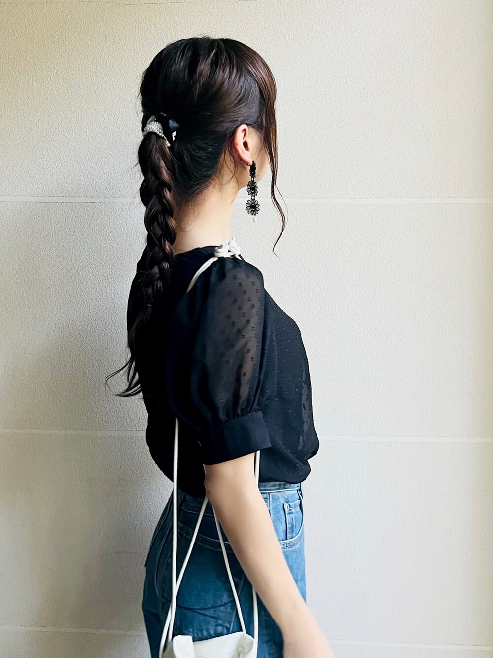 ブラック系のパンプス、ホワイト系のショルダーバッグ、ブルー系のデニムパンツを着用したレディースの秋コーディネートの2枚目の写真