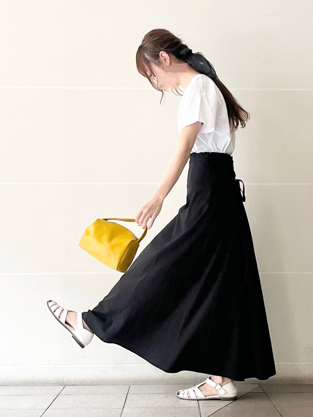 ホワイト系のTシャツ/カットソー、イエロー系のハンドバッグ、ブラック系のスカートを着用したレディースの春コーディネートの2枚目の写真