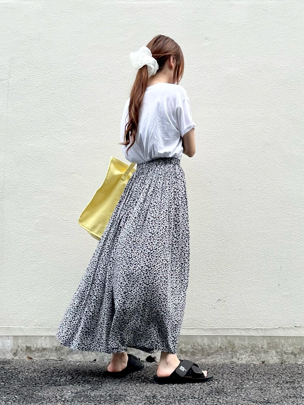 イエロー系のトートバッグ、ホワイト系のTシャツ/カットソー、ブラック系のスカートを着用したレディースの夏コーディネートの2枚目の写真