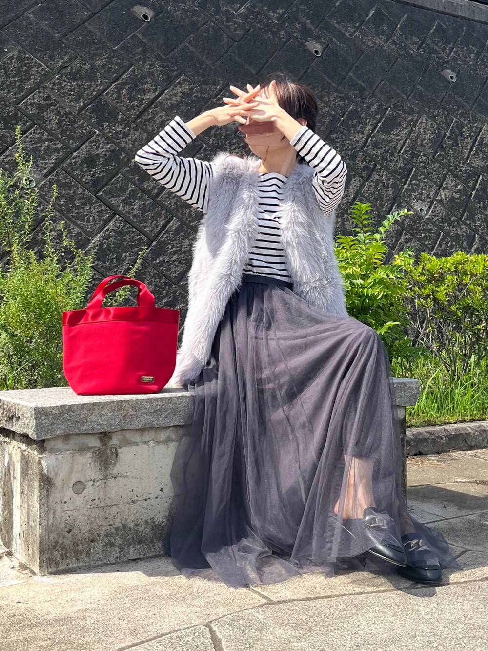 グレー系のベスト、ブラック系のスリッポン、グレー系のスカートを着用したレディースの秋コーディネートの3枚目の写真