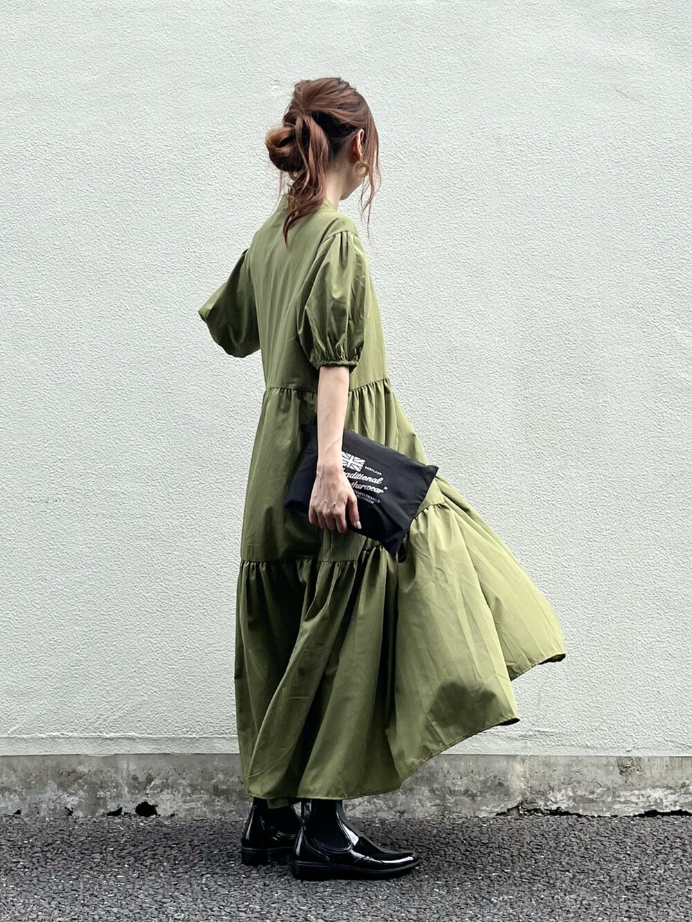 ブラック系のレインシューズ、グリーン系のワンピース、ブラック系のレインコート/ポンチョを着用したレディースの春コーディネートの3枚目の写真