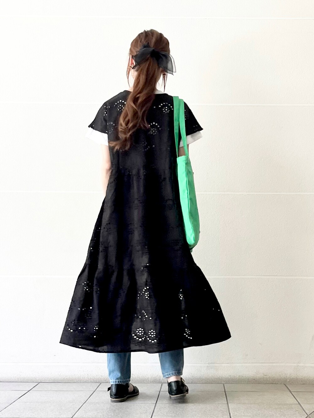 ブラック系のワンピース、ホワイト系のTシャツ/カットソー、グリーン系のトートバッグを着用したレディースの春コーディネートの2枚目の写真