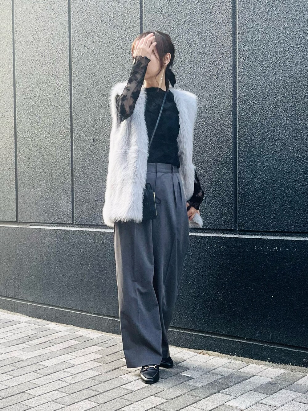 グレー系のベスト、ブラック系のショルダーバッグ、ブラック系のローファーを着用したレディースの冬コーディネートの2枚目の写真