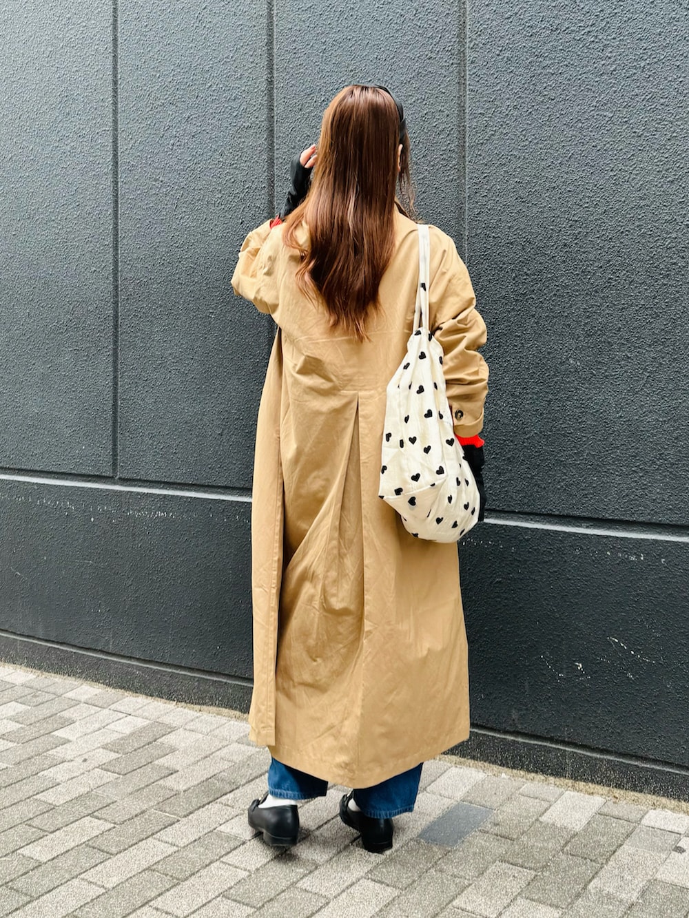 ベージュ系のステンカラーコート、レッド系のニット/セーター、ブラック系のローファーを着用したレディースの春コーディネートの2枚目の写真
