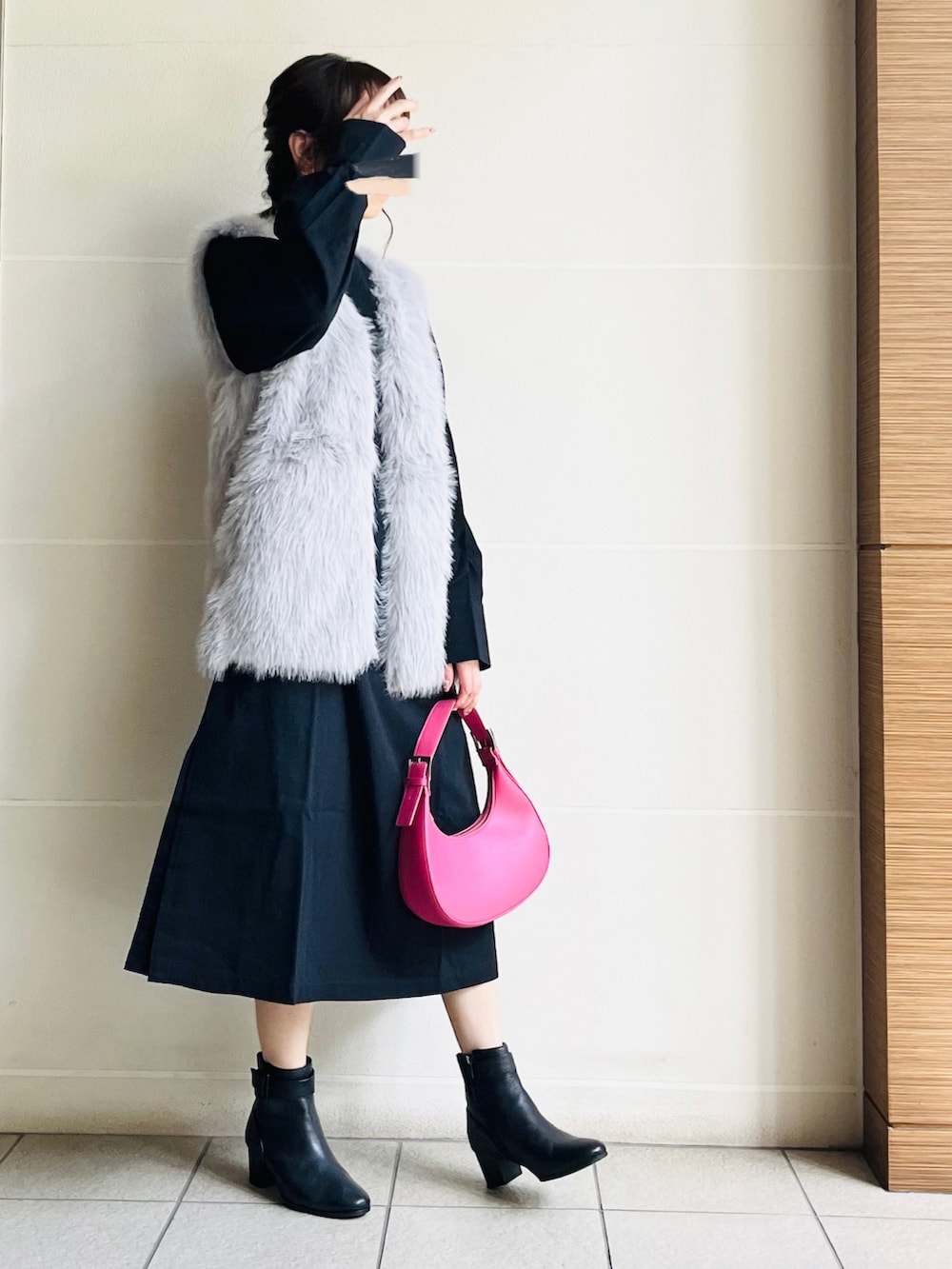 グレー系のベスト、ブラック系のワンピース、ブラック系のブーツを着用したレディースの秋コーディネートの2枚目の写真