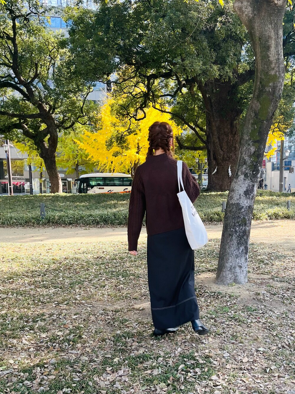 ホワイト系のトートバッグ、ブラック系のスカート、ブラック系のブーツを着用したレディースの冬コーディネートの2枚目の写真