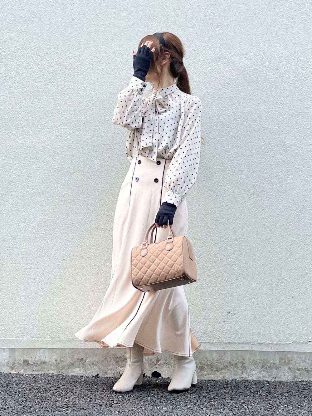 ベージュ系のスカート、ベージュ系のハンドバッグ、ホワイト系のブーツを着用したレディースの秋コーディネートの3枚目の写真