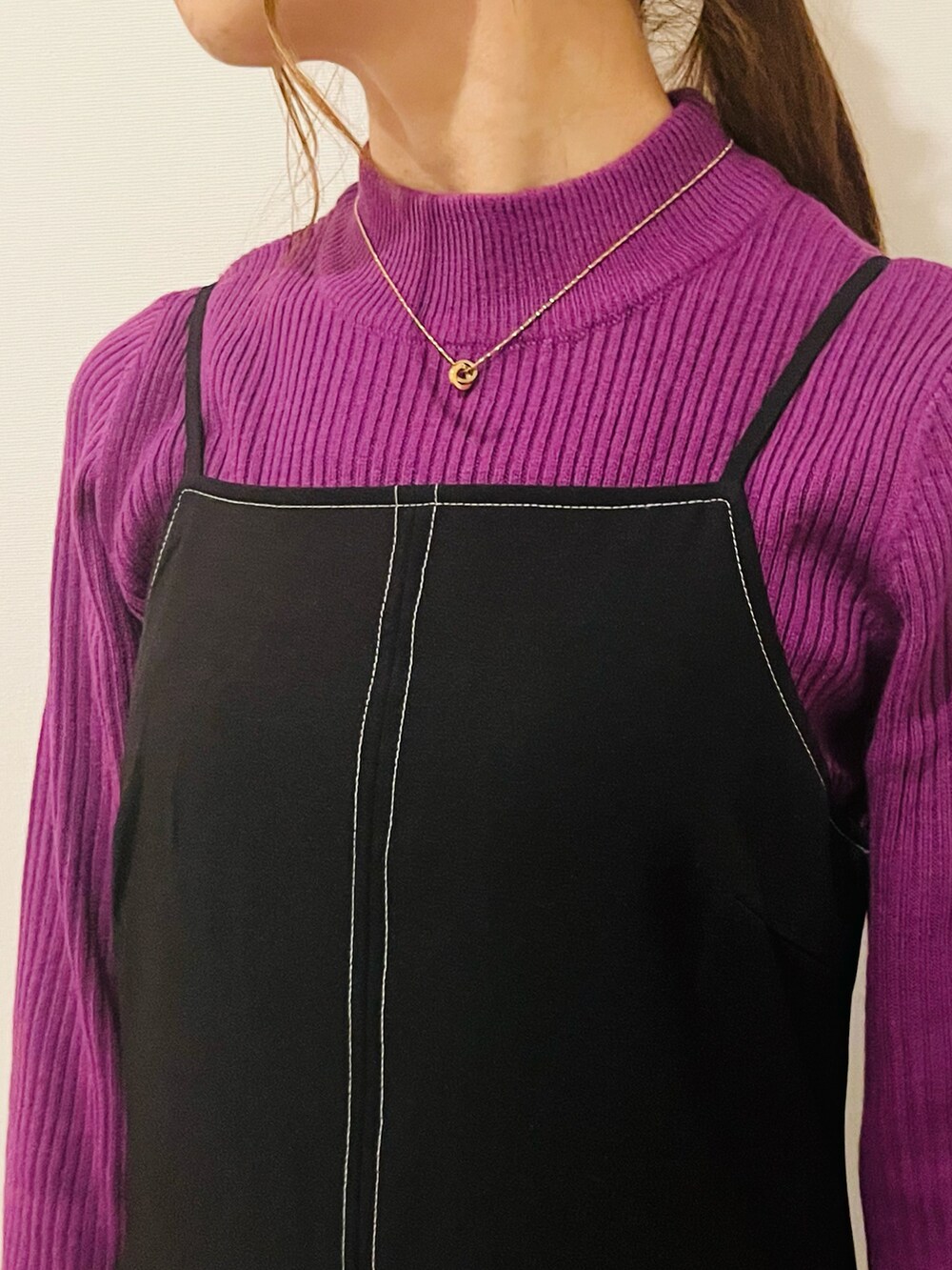 パープル系のニット/セーター、ブラック系のワンピース、ブラック系のブーツを着用したレディースの冬コーディネートの2枚目の写真