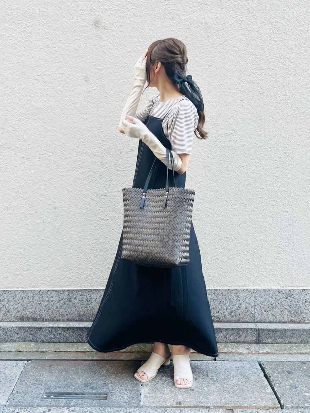 ブラウン系のバッグ、ブラック系のワンピース、ホワイト系のニット/セーターを着用したレディースの春コーディネートの4枚目の写真
