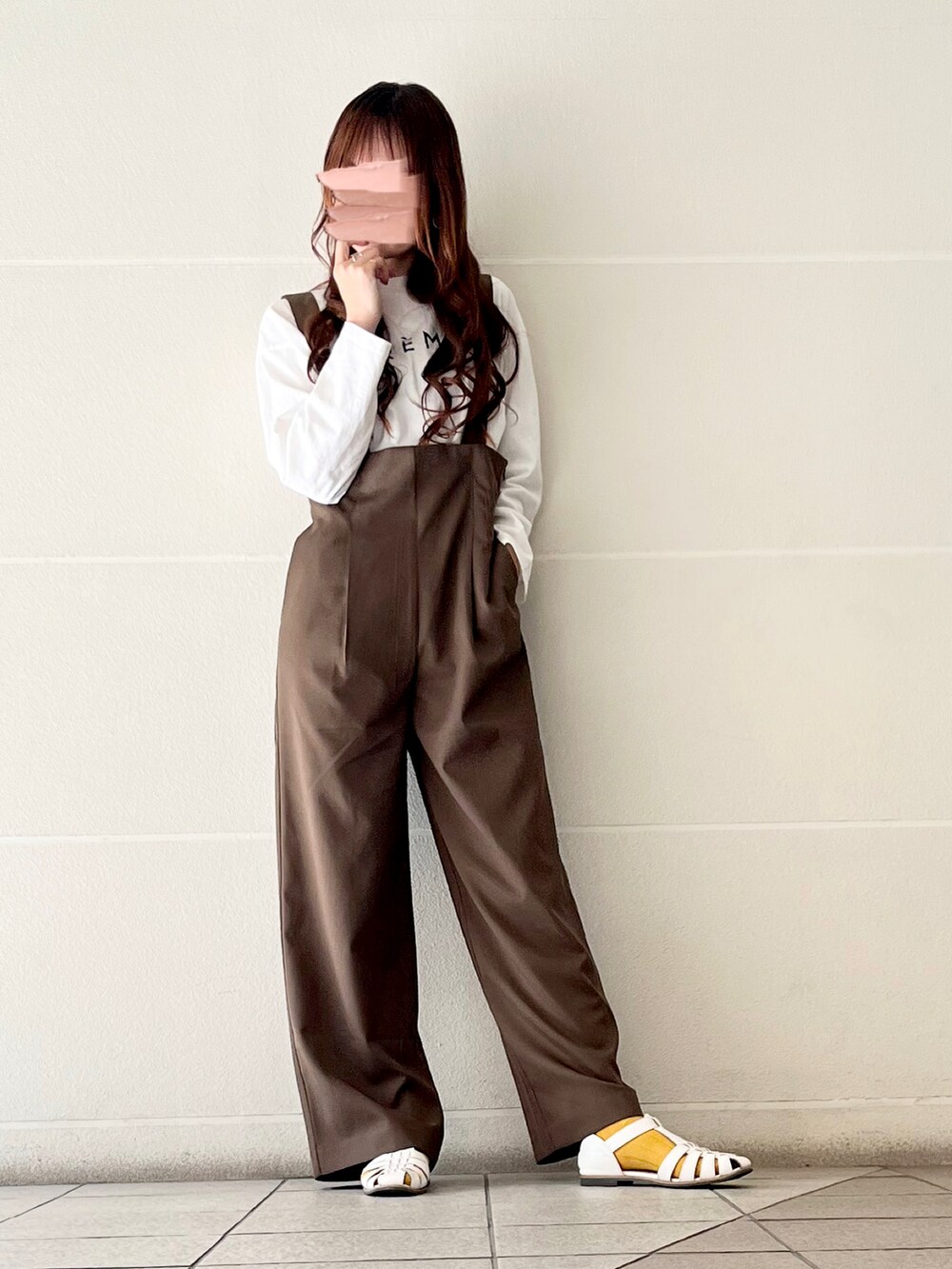 ブラウン系のサロペット/オーバーオール、イエロー系のハンドバッグ、ホワイト系のTシャツ/カットソーを着用したレディースの冬コーディネートの3枚目の写真