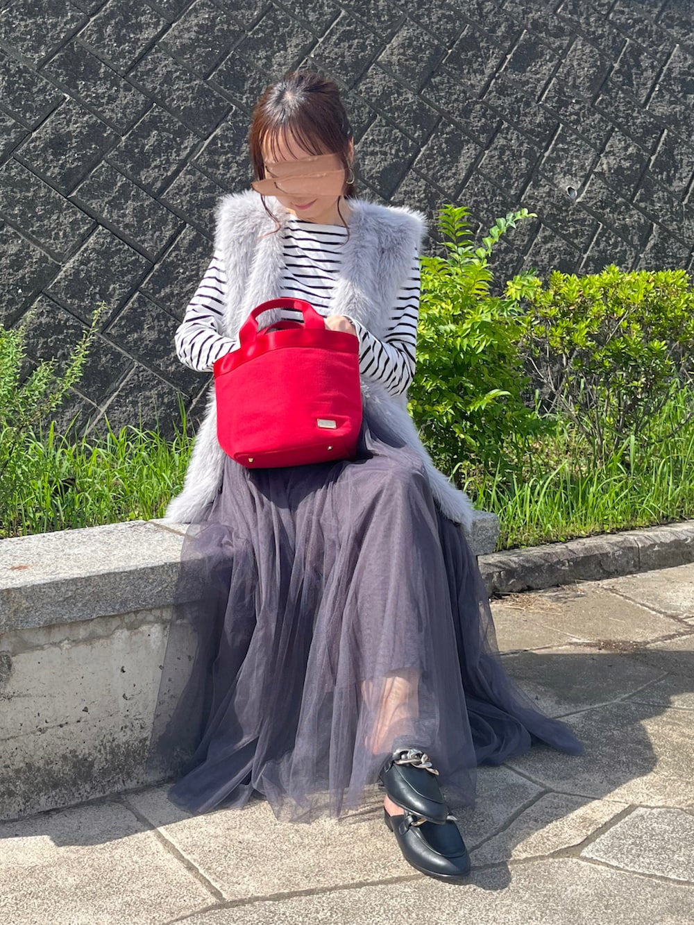 グレー系のベスト、ブラック系のスリッポン、グレー系のスカートを着用したレディースの秋コーディネートの2枚目の写真