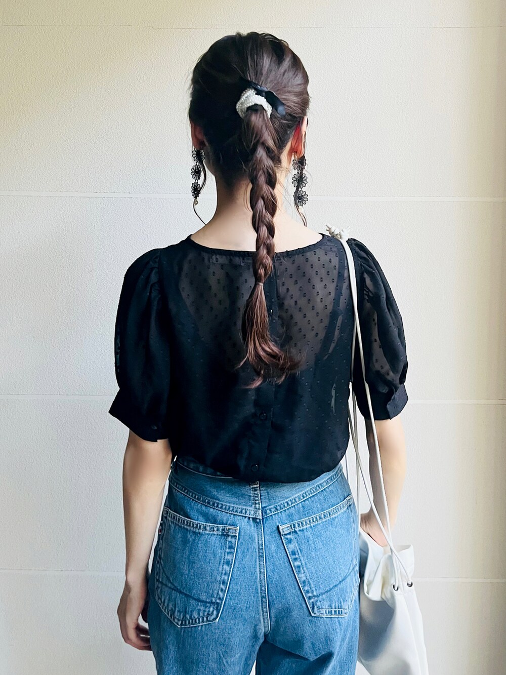 ブラック系のパンプス、ホワイト系のショルダーバッグ、ブルー系のデニムパンツを着用したレディースの秋コーディネートの3枚目の写真