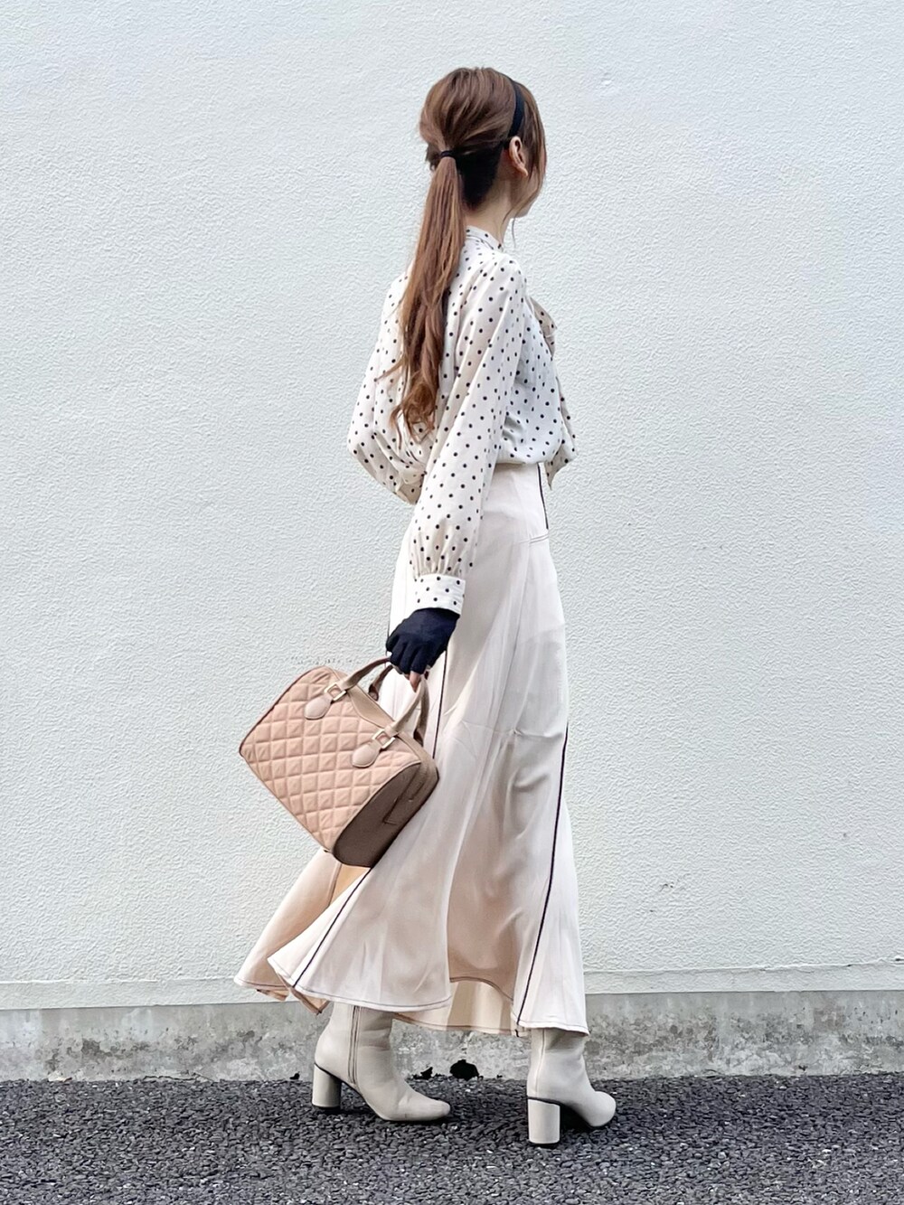 ベージュ系のスカート、ベージュ系のハンドバッグ、ホワイト系のブーツを着用したレディースの秋コーディネートの2枚目の写真